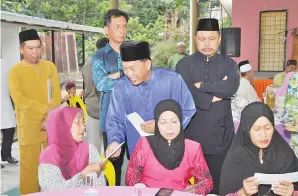  ??  ?? RAIME menyampaik­an sumbangan dari Kumpulan Yayasan Sabah kepada salah seorang penerima. Turut kelihatan Teo (berdiri dua kiri).