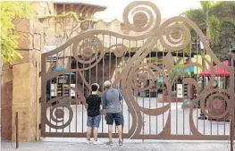  ?? STEPHEN M. DOWELL/ORLANDO SENTINEL ?? On May 14, guests peer through the closed gate to Universal’s Islands of Adventure beside Universal CityWalk, in Orlando. Universal Orlando is aiming to reopen its theme parks in early June, a resort official said Thursday more than two months after closing.