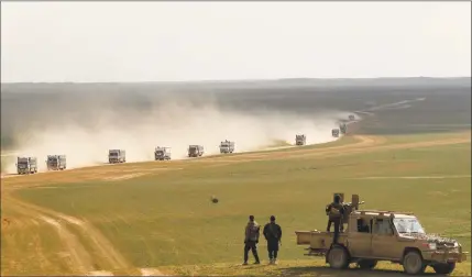  ?? Delis Souleiman/ AFP/Getty Images ?? Syrian Democratic Forces fighters stand guard as a convoy of truck transports civilians fleeing the battered Islamic State-held holdout of Baghouz in the eastern Syrian province of Deir Ezzor on Monday.