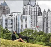  ?? JOHN SPINK/JOHN.SPINK@AJC.COM ?? Ron Hoffman enjoys a nice Tuesday in Piedmont Park with his dog, Georgia. As the summer months bring higher temperatur­es, they also bring severe storms and hurricane season, an ever-evolving threat to the state, thanks to climate change.