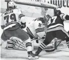  ?? GENE J. PUSKAR/AP ?? The Penguins’ Sidney Crosby, right, pokes the puck under the pad of Rangers goaltender Igor Shesterkin, middle, during the first period in Game 4 Monday in Pittsburgh.