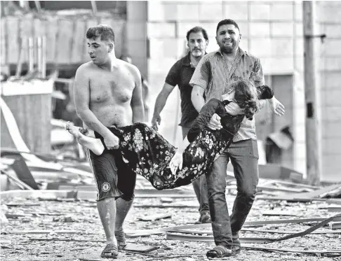  ?? AP PHOTO ?? DEVASTATIO­N. Lebanese Red Cross said at least 100 people were killed and more than 4,000 were wounded following a massive explosion at the port of Beirut, Lebanon on Tuesday, August 4, 2020. Men evacuate a wounded woman after the explosion.