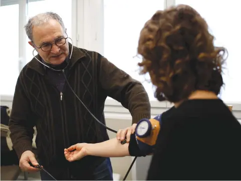  ?? (Stephane Mahe/Reuters) ?? RETIRED FRENCH doctor Jean-Francois Rechner, 67, measures the blood pressure of a patient during a consultati­on at the ‘Service Medical de Proximite’ clinic in Laval, France.