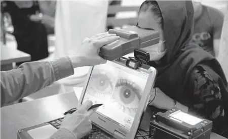  ?? RAHMAT GUL/AP ?? An employee scans the eyes of a woman for biometric data needed to apply for a passport at the passport office in Kabul, Afghanista­n.