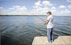  ?? SHELBY TAUBER / AMERICAN-STATESMAN ?? Felipe Mayo fishes at Walter E. Long Lake on Thursday. The land across the lake is where some hope to revive the idea of a golf course and other developmen­t. Fifty years ago, the city had big plans for the land, but not much has happened.