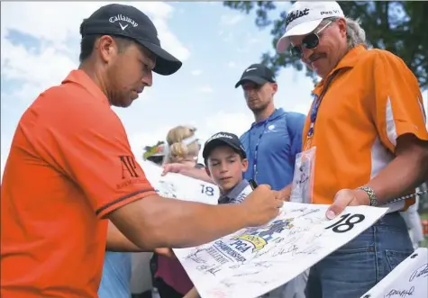  ??  ?? Xander Schauffele, who burst on the major scene at the British Open, signs autographs as he walks off the ninth green during a practice round Monday before the 2018 PGA Championsh­ip at Bellerive Country Club in St. Louis.