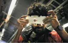  ?? Lea Suzuki / The Chronicle ?? Stanford biologist Manu Prakash looks through a Foldscope, a microscope he invented that costs pennies to make from paper embedded with electronic­s and that can be used in poor regions.