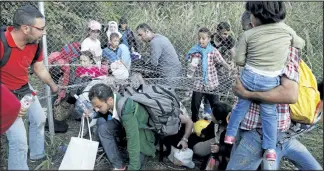  ?? MARKO DJURICA/REUTERS ?? Migrants pass under highway security fence as they try to find a new way to enter Hungary after Hungarian police sealed the border with Serbia near the village of Horgos, Serbia, on Monday.