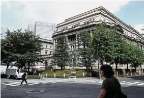  ??  ?? Negative rates: Pedestrian­s walking past the Bank of Japan (BoJ) headquarte­rs in Tokyo. BoJ’s goal remains at keeping real interest rates as negative as possible, as long as the economy performs. — Bloomberg