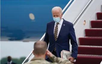  ?? Getty Images ?? CHECK THE REVIEWS: President Biden carries a handful of newspapers after arriving Friday at Dover Air Force Base in Delaware. Biden will spend the weekend in Rehoboth Beach, Del.