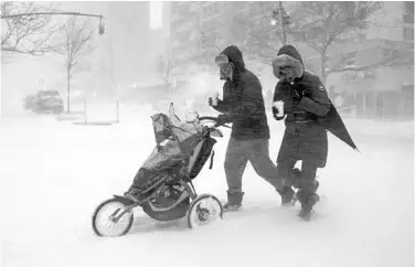  ?? CRAIG RUTTLE/ASSOCIATED PRESS ?? Sean Jackson and Gina Del Tatto push their child, Hayes Jackson, in a stroller as heavy snow falls in New York’s Upper West Side. Most of the East Coast was expecting snow totals close to 2 feet, with 25 to 30 inches expected in New York City.