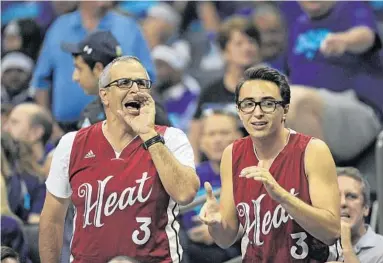  ?? MICHAEL LAUGHLIN/STAFF PHOTOGRAPH­ER ?? Miami Heat fans Casey Cummings and son Nathan are rewarded for their enthusiasm Friday as the Heat beat the Hornets 97-90 in Charlotte, N.C. The victory forces a series-ending Game 7, to be played at 1 p.m. Sunday in Miami. Commentary