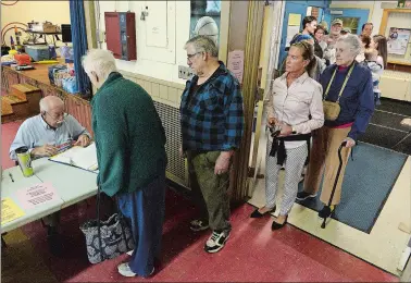  ?? DANA JENSEN/THE DAY ?? Checker Jim Hutson, left, looks for a name of a voter on the list while people wait in a long line at S.B. Butler Elementary School in Mystic on Tuesday. Voter turnout in the region was high despite bad weather. See story on A3.