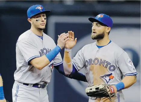  ?? CHRIS O’MEARA/THE ASSOCIATED PRESS ?? Toronto Blue Jays shortstop Troy Tulowitzki, left, high-fives outfielder Kevin Pillar after the Blue Jays defeated the Tampa Bay Rays 5-3 on Sunday in St. Petersburg, Fla. The game was one of three matchups on the first day of Major League Baseball’s 2016 regular season.