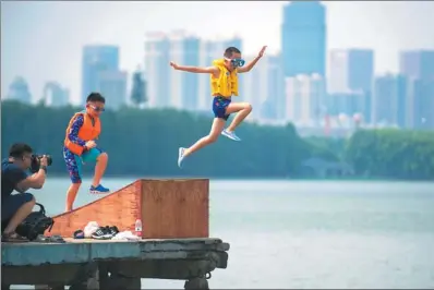  ?? LIU ZHONGCAN / FOR CHINA DAILY ?? Children escape the summer heat on Sunday by leaping into Donghu Lake in Wuhan, Hubei province, as a photograph­er records the action. The lake has served for years as an informal gathering place during hot weather.