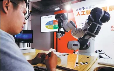  ?? TANG YANJUN / CHINA NEWS SERVICE ?? A visitor to the 2018 World Artificial Intelligen­ce Conference, which opened on Monday in Shanghai, plays Go with a robot.