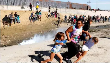  ??  ?? File photo shows Meza (centre) from Honduras, part of a caravan of thousands from Central America running away from tear gas with her five-year-old twin daughters in front of the US-Mexico border wall in Tijuana. — Reuters photo