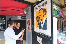  ?? AFP ?? Men look at a poster in Tunis of the movie Papa Hedi: The man behind the microphone, dedicated to the great Tunisian singer Hedi Jouini and directed by his granddaugh­ter Claire.