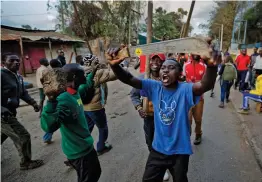  ??  ?? Opposition supporters carrying rocks and a machetes as they try to march down a road leading out of the Kawangware area, before being pushed back by police firing tear gas, in Nairobi on Saturday. —