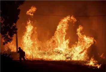  ?? Noah Berger/Associated Press ?? A firefighte­r passes flames from a backfire while battling the Delta Fire on Sept. 6, 2018, in the Shasta-Trinity National Forest, Calif.