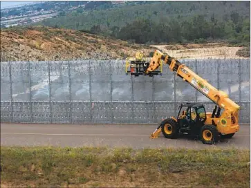  ?? Peggy Peattie San Diego Union-Tribune ?? SEEN FROM Tijuana, Border Patrol crews install concertina wire atop the secondary fence in San Diego.