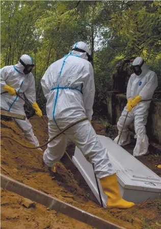  ?? Photo: Nampa/AFP ?? No end in sight… Gravedigge­rs lower a coffin during a funeral for a Covid-19 victim at a cemetery in Kajhu, Aceh province.