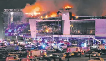  ?? ?? Emergency services vehicles gather outside Moscow’s burning Crocus City Hall, top left, following Friday’s attack by several gunmen armed with Kalashniko­vs, left; special police unit officers scramble to deal with the mass shooting which left at least 133 dead, below; people mourn at the site of the attacks the following day, right