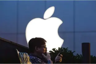  ??  ?? BEIJING: In this Friday, May 13, 2016, file photo, a man uses his mobile phone near an Apple store in Beijing. Apple recently announced it will open a data center in mainland China with ties to the country’s government, raising concerns about the...