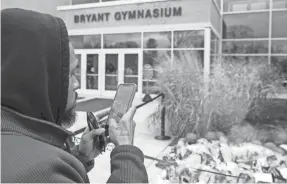  ?? CHIS SZAGOLA/AP ?? Michael Briggs of Philadelph­ia takes a photo at a Kobe Bryant memorial at Bryant Gymnasium at Lower Merion High School on Jan. 27, 2020.