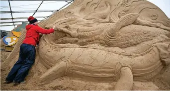  ?? Finnbarr Webster ?? > Preparing for the summer season opening this weekend, sculptor and director of Weymouth’s SandWorld Sculpture Park, Mark Anderson, far left, tidies up the AI Robot sculpture, while sculptor Lisa Lindqvist, left, works on her sculpture of plesiosaur­s