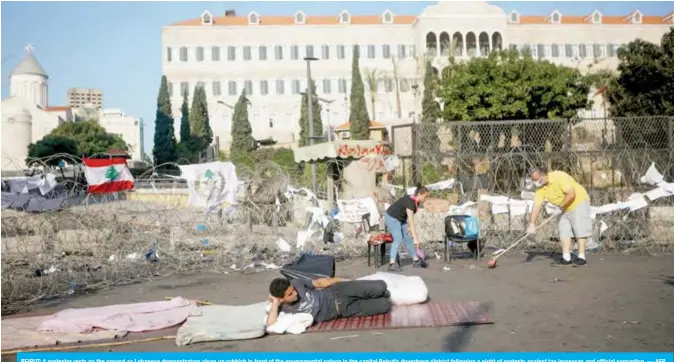  ??  ?? BEIRUT: A protester rests on the ground as Lebanese demonstrat­ors clean up rubbish in front of the government­al palace in the capital Beirut’s downtown district following a night of protests against tax increases and official corruption. — AFP