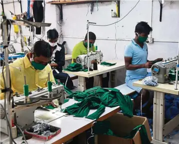  ?? AFP ?? Economic devastatio­n: Workers manufactur­e face masks at a workshop in Mumbai. India’s PMI figures provide the first real glimpse of the devastatin­g hit to the economy from the coronaviru­s pandemic and the nationwide shutdown that came into effect in the last week of March. —