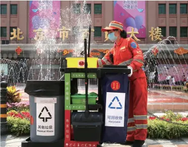  ??  ?? A street cleaner at work with her cart, carrying four dustbins for four different categories of garbage at Wangfujing Street in downtown Beijing on May 29