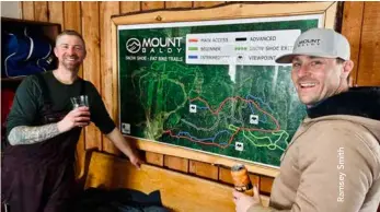  ?? ?? ▼ Brandon Smith and Garth Kayes with a wall map of the winter trails inside Mount Baldy’s chalet