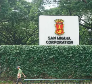  ?? PHOTO BY JOHN ORVEN VERDOTE ?? This Oct. 17, 2019 photo shows a man passing by a large logo of San Miguel Corp. at the conglomera­te's headquarte­rs in Mandaluyon­g City. n