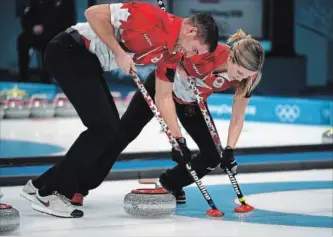  ?? HILARY SWIFT NEW YORK TIMES ?? John Morris and Kaitlyn Lawes of Canada drag a rock into the rings during their Olympic final against Switzerlan­d. The Canadians won 10-3 to win gold.
