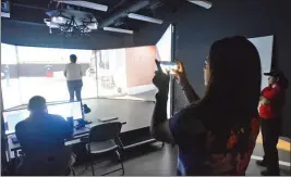  ??  ?? Jennifer Tagaban (second from right) makes a cell phone video of her mother Leticia Tagaban participat­ing in a simulated police situation inside the VirTra simulator. Yuma Police Department Lt. Claudia Leyva (right) and YPD officer Kyle Dandoy (left) observe.