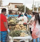  ??  ?? Local farmers, wearing protective gear, sell their products to residents May 2 in San Cristobal, Galapagos Islands.