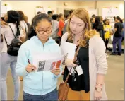  ??  ?? Eighth grader Kelsie Luna, left, and social studies teacher Taylor Gross from Theodore G. Davis Middle School take some time out to read their informatio­n sheets at the showcase.