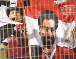  ??  ?? Egyptian fans hold an image of Mohamed Salah in a stadium in Cairo. –
