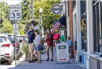  ?? ALYSSA POINTER / ALYSSA.POINTER@AJC.COM ?? People stroll Stonewall Avenue recently in downtown Fayettevil­le. This fall ground gets broken on a $23M City Hall and center city park complex officials hope draws more foot traffic.