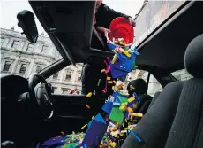  ?? LEON NEAL/AFP/GETTY IMAGES ?? Donors pour Lego bricks through the sunroof of a car in London, which is being used as a receptacle for donations to Chinese artist and activist Ai Weiwei, who wants to use Lego for his next art project.