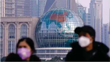  ?? — Reuters ?? People wearing protective masks are pictured at The Bund in front of the Lujiazui financial district of Pudong in Shanghai, China.