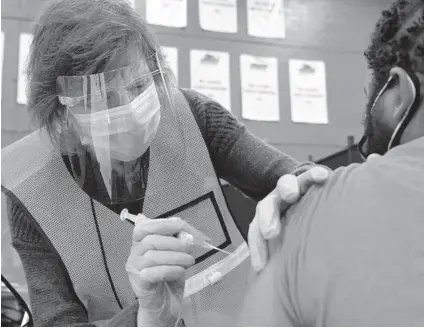  ?? KARL MERTON FERRON/BALTIMORE SUN PHOTOS ?? Patty Herwig, a nurse at Kennedy Krieger Institute, administer­s the second inoculatio­n for William Bevan as eligible residents receive the followup Moderna dose Wednesday at Baltimore City Community College.