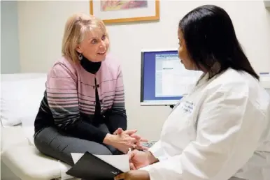  ??  ?? Legacy Health’s Dr. Angela Lewis-traylor, right, speaks with a patient. “We’re about 40% of the Medicaid population in the state of Oregon,” said Legacy president and CEO Brown of the three-county Portland area.