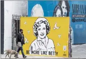  ?? CHRIS PIZZELLO — THE ASSOCIATED PRESS ?? A man walks a dog past a new mural of the late actress Betty White by artist Corie Mattie in Los Angeles.