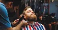  ?? ?? Greg Smith receives a haircut at St Kilda’s Peaky Blinders Barber Shop on the second day of eased Covid-19 regulation­s, in Melbourne.