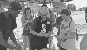  ??  ?? Kerry Hanan, center, Silph Road master guide for the West Tennessee/North Mississipp­i area, helps a “Pokemon Go” trainer during a recent meetup at Olive Branch City Park. RAINA HANNA / FOR COMMERCIAL­APPEAL.COM