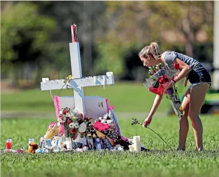 ?? AP ?? A woman places flowers yesterday at one of 17 crosses erected for the victims of the mass shooting at Marjory Stoneman Douglas High School, in Parkland, Florida. Nikolas Cruz, a former student at the school, has been charged with 17 counts of premeditat­ed murder.