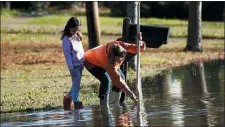  ?? ROGELIO V. SOLIS - THE ASSOCIATED PRESS ?? Barbara Beavers marks a pole used to measure the flooding on her street, as her granddaugh­ter McRee Raggio, 7, checks to make sure the measuring is accurate in northeast Jackson, Miss., Friday, Feb. 14. As of Friday afternoon, the Pearl River was at 35.48 feet, which is more than 7feet above flood stage. On Sunday, the river is expected to crest at 38feet. Only twice before has the Pearl River surpassed 38feet — during the historic floods of 1979 and 1983.